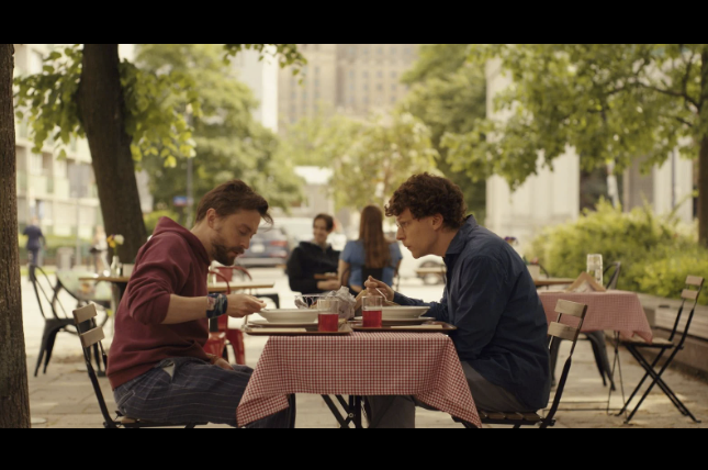 Scène extraite du film A Real Pain : David et Benji mangeant en terrasse à Varsovie.